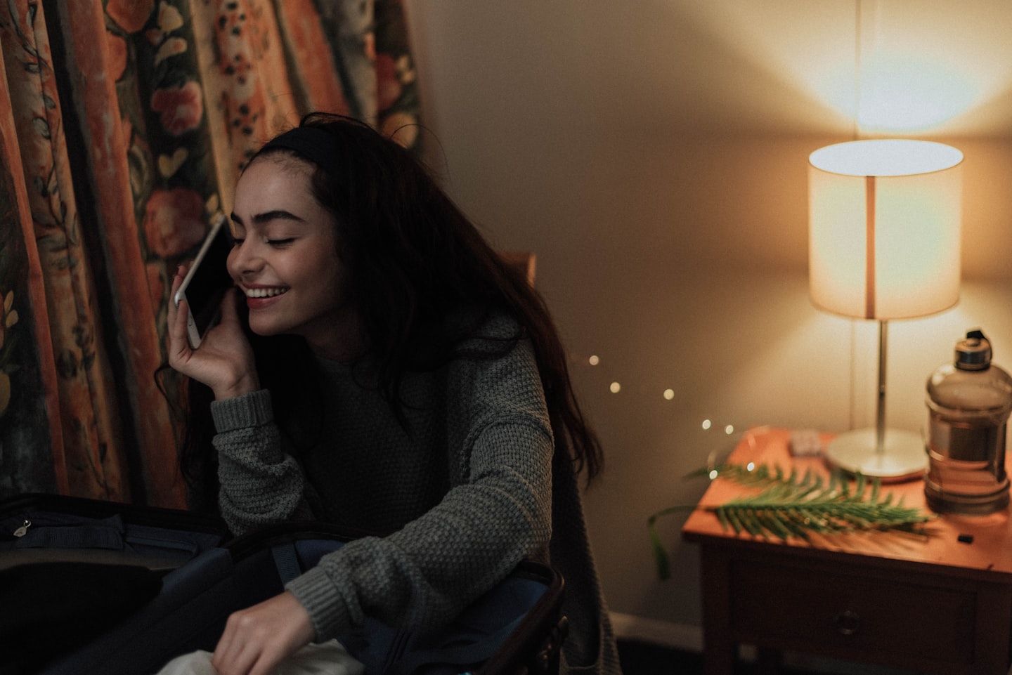 Smiling woman texting at night, representing romance-first AI companion chat and emotional continuity