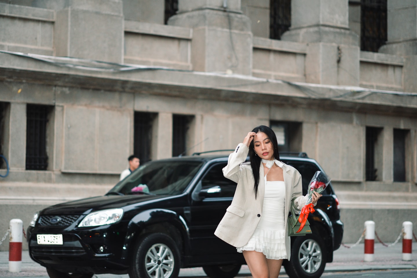 a woman in a white dress is walking down the street