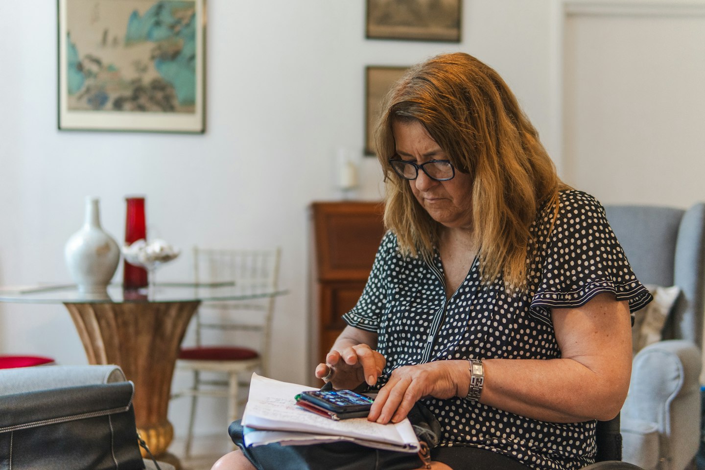 Woman using calculator with papers on table