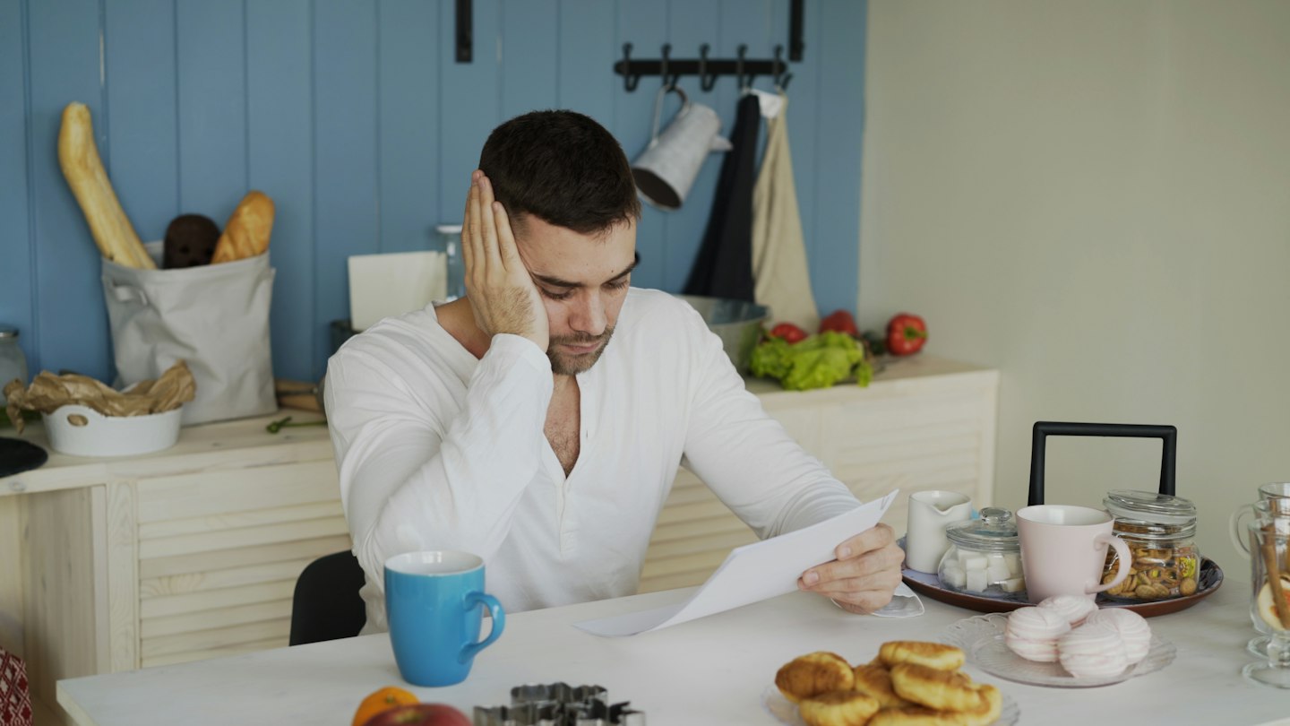 Man sitting at table reading papers with breakfast