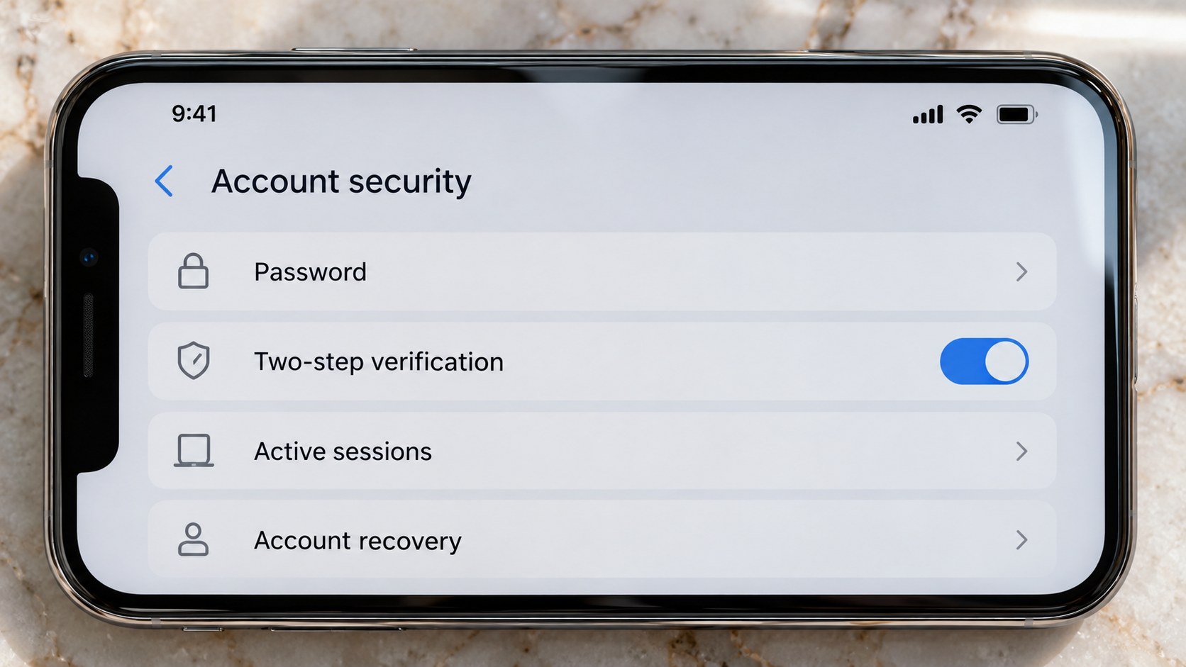 Close frontal view of a smartphone displaying account security settings on a pale stone surface in natural light.